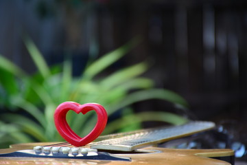 Red wood heart put on guitar for love on nature background