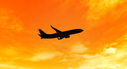 Silhouette of an airplane taking off on sunset background