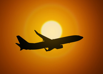 Fototapeta na wymiar Silhouette of an airplane taking off on sunset background