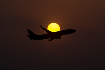 Naklejka na ściany i meble Silhouette of an airplane taking off on sunset background