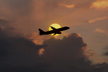 Silhouette of an airplane taking off on sunset background