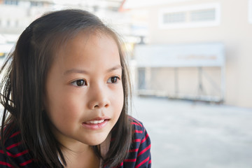 Adorable asian kid wear black and red striped shirt smiling in a restaurant.