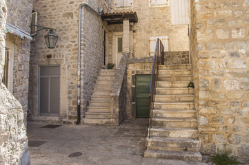 Fototapeta na wymiar The courtyard of one of the houses in the Old Town of Budva, Montenegro, with stairs and old lantern