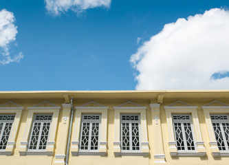 Old yellow building with blue sky and white clouds background.