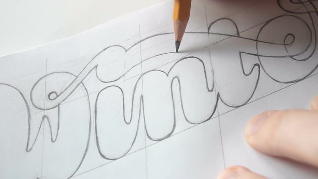 Lettering or logo creating with a pencil on white paper. Handlettering design. Designer drawing letters with pen. Sketch artwork. Calligraphy work.
