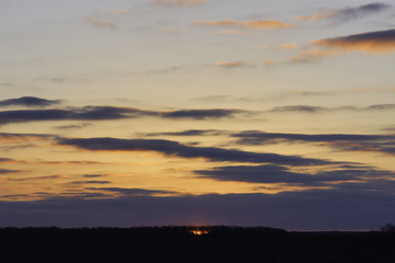 Fiery red sun peeking through trees on the horizon at sunrise