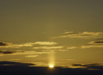 Golden sun peeking above clouds horizon, early morning