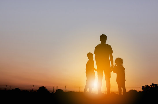 Silhouette of Father and two kids having fun on sunset, Happy family concept.