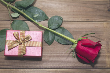 gift box and red roses upon wood