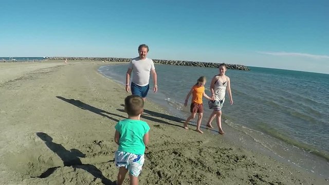 Girl collect seashells near the seashore with parents