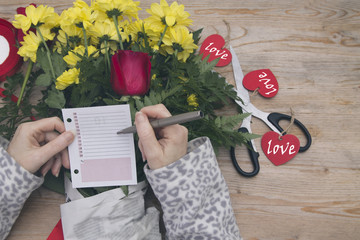 preparing bouquet of roses and note for Valentine's day