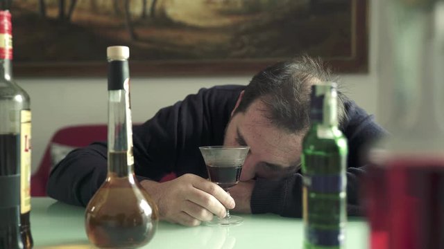 drunk man sad and desperate drinking yet another glass of wine