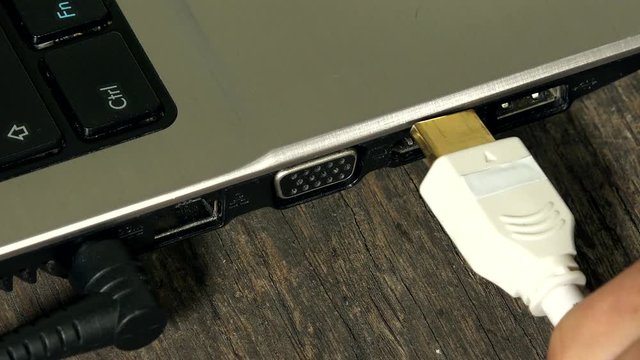 Fingers connecting hdmi wire to laptop computer