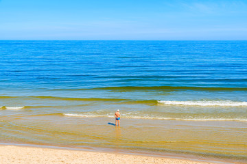 Man standing in water on beach in Jastrzebia Gora, Baltic Sea, Poland
