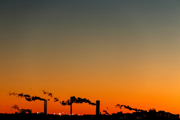 Industrial sunset. Beautiful colored sky and industrial chimneys exhaling smoke.