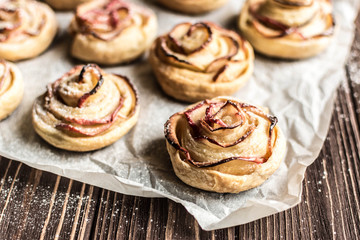 Obraz na płótnie Canvas Apple rose puff pastries sprinkled with powdered on baking paper