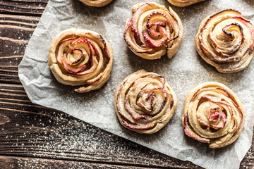 Apple rose puff pastries sprinkled with powdered on baking paper