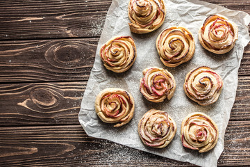 Apple rose puff pastries sprinkled with powdered on baking paper