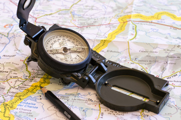 prepare a road trip, still life with a compass and over a map. the yellow line indicate the path. travel. journey. direction.