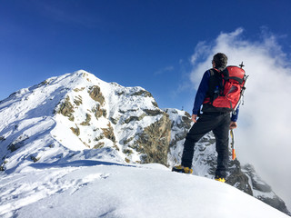 Hiker looks at a winter mountain landscape. European Alps.