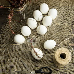 White easter eggs decorated with dried flowers and pink rope