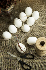 White easter eggs decorated with dried flowers and pink rope