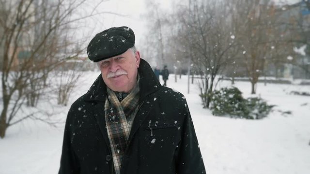 aged man walking on the street , snowfall, slow motion