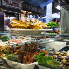 Shrimps, bamboo jack knife clams and mussels on ice in glass case of cafe at Mercat de Sant Josep, Boqueria market Barcelona Spain. Fried Gould's razor shell or Canyut navaja in olive oil and pesto