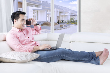Handsome man talks on cellphone at couch