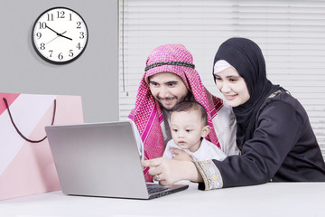 Happy arabian family looking at laptop