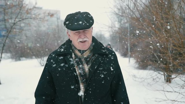 old man cleans car windows from snow , snow falls, slow motion