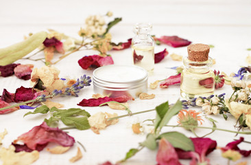 Dried holistic herb blend and extracted cosmetic beauty care products. Flowers, cream, oil bottle. Soft light, toned.