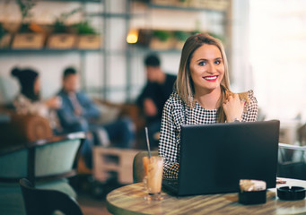 Young gorgeous woman sitting in front of open laptop computer in cafe bar