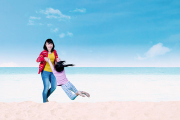 Mother swinging her daughter on beach