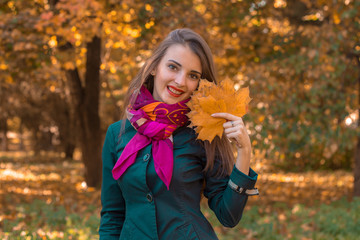 girl stands in autumn Park and keeps the leaves in hand