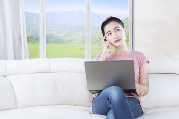 Pensive woman with laptop in living room