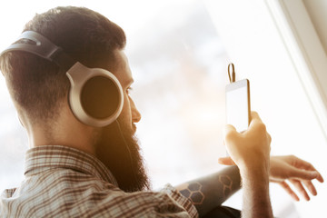 bearded man in headphones listening to music with smartphone app