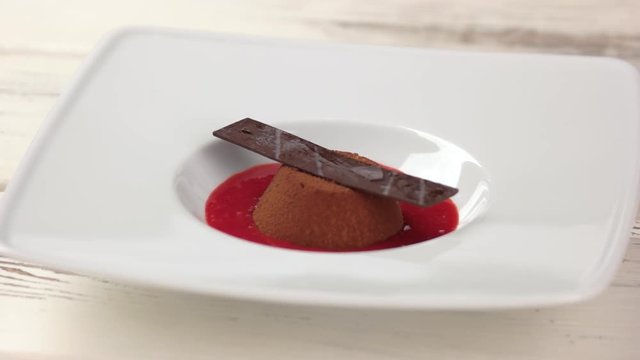 Dessert with chocolate decoration. Cake served with strawberry sauce.