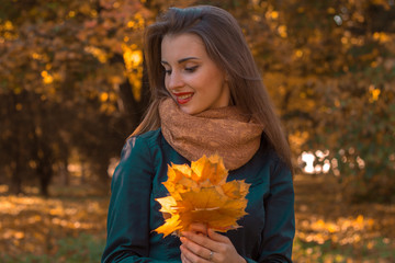 beautiful girl smiling and holding a maple leaf in the hands