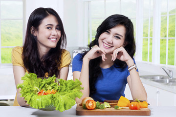 Two healthy girls holds a bowl of salad