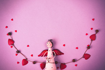 Levitating Angel with hearts and bells. Symbol of love. The concept  Valentine's Day. Pink background