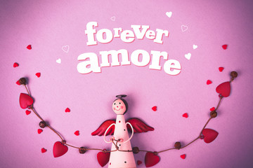 Levitating Angel with hearts and bells. Symbol of love. The concept  Valentine's Day. Inscription Forever Amore. Pink background