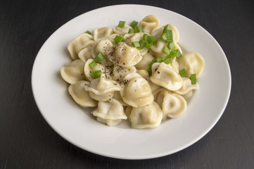 Russian dumplings in a white plate on a black background