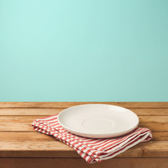 Empty white plate on wooden table over mint wallpaper background
