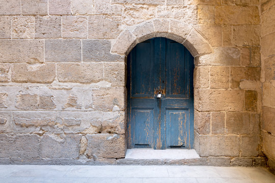 Blue wooden stained aged vaulted ornate door and stone wall