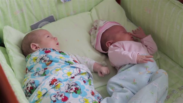 twins baby girl and boy/two twins babies lying in cots