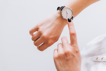 A young business woman checks time on her classic watch, she thinks about time management and...