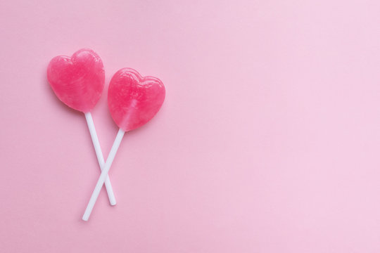 two Pink Valentine's day heart shape lollipop candy on empty pas