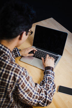 Programmer in the office working on the computer on a wooden desk