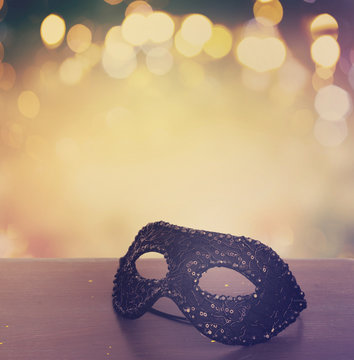 Mask on wooden table border isolated on bokeh background with copy space, retro toned